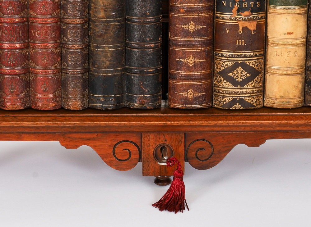 An antique Victorian walnut tabletop collectors cabinet featuring a front styled with vintage book spines, turned columns, turned feet, and a central finial top. View V