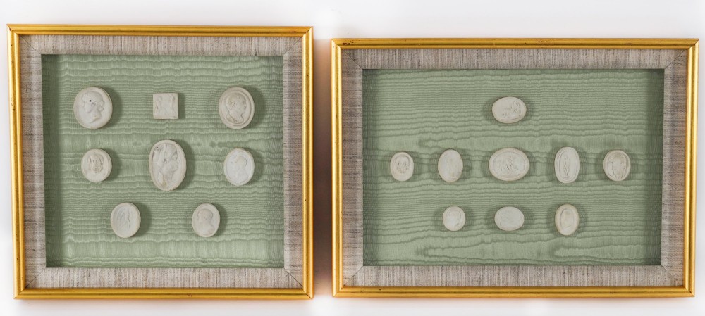 A pair of framed displays containing white plaster intaglio relief medallions mounted on green patterned fabric inside gilt frames. View II