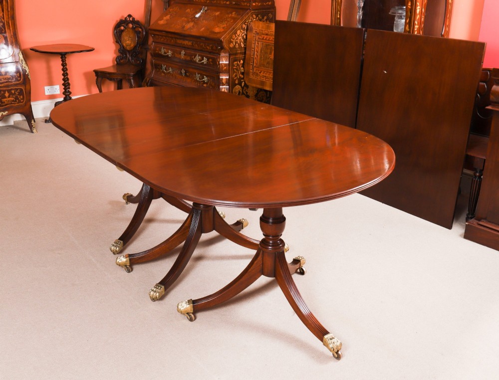 An extended mahogany Regency Revival triple pillar dining table with reeded legs and brass paw castors. View V