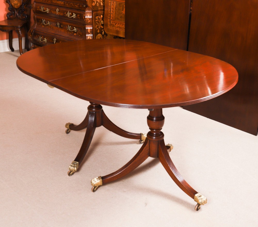 An extended mahogany Regency Revival triple pillar dining table with reeded legs and brass paw castors. View VI