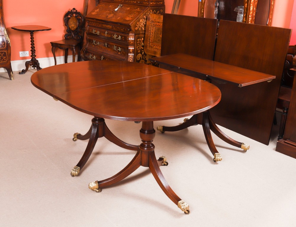An extended mahogany Regency Revival triple pillar dining table with reeded legs and brass paw castors. View VII