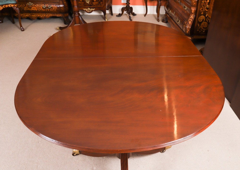 An extended mahogany Regency Revival triple pillar dining table with reeded legs and brass paw castors. View IX