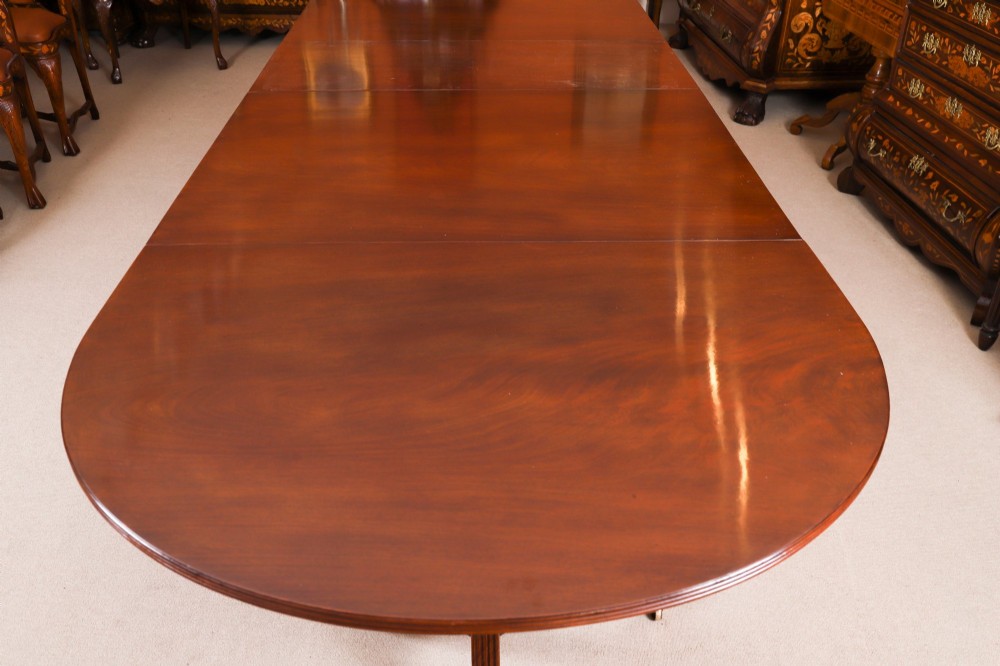 An extended mahogany Regency Revival triple pillar dining table with reeded legs and brass paw castors. View XI