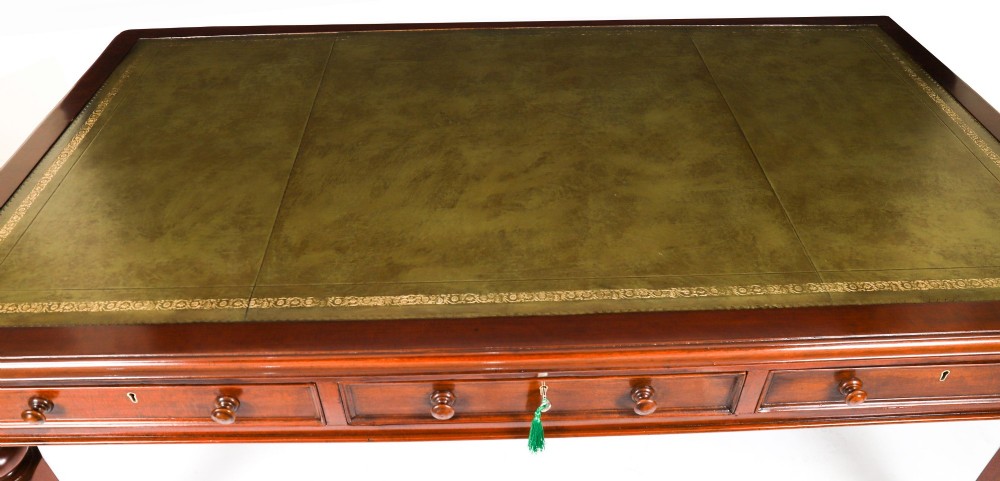 A nineteenth-century mahogany partners writing table featuring a green leather inset surface, six drawers with turned knobs, and octagonal turned legs on brass castors. View V