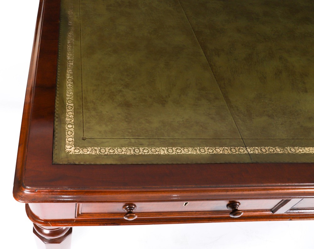 A nineteenth-century mahogany partners writing table featuring a green leather inset surface, six drawers with turned knobs, and octagonal turned legs on brass castors. View VI