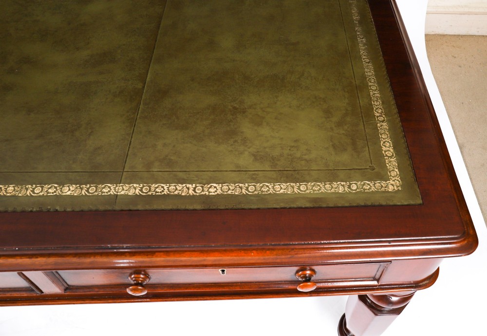 A nineteenth-century mahogany partners writing table featuring a green leather inset surface, six drawers with turned knobs, and octagonal turned legs on brass castors. View VII