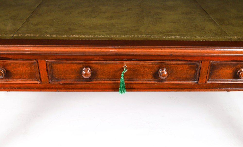 A nineteenth-century mahogany partners writing table featuring a green leather inset surface, six drawers with turned knobs, and octagonal turned legs on brass castors. View IX