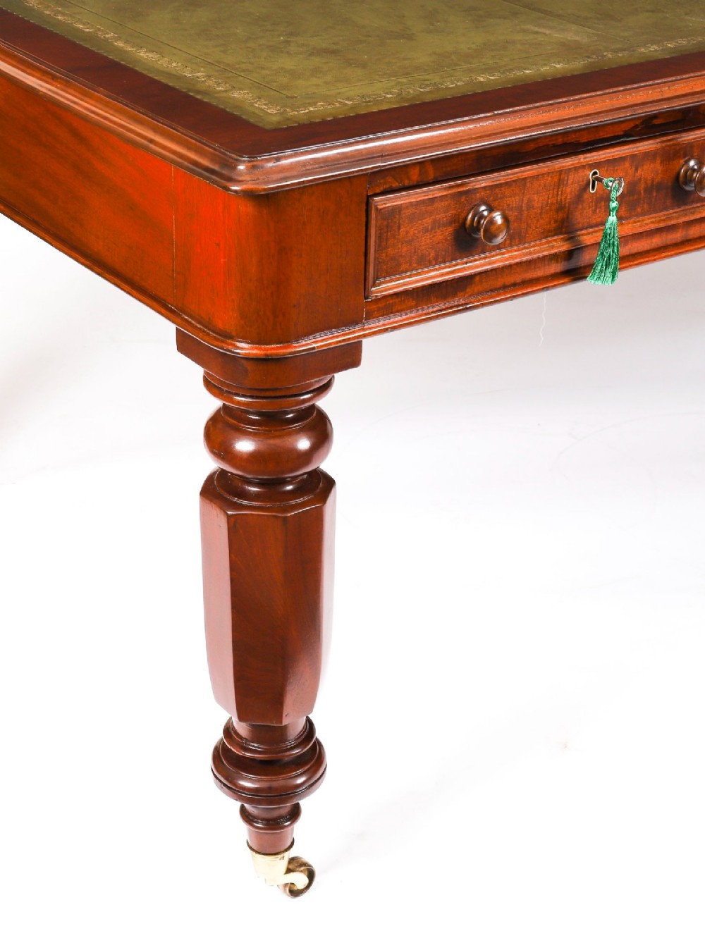 A nineteenth-century mahogany partners writing table featuring a green leather inset surface, six drawers with turned knobs, and octagonal turned legs on brass castors. View X