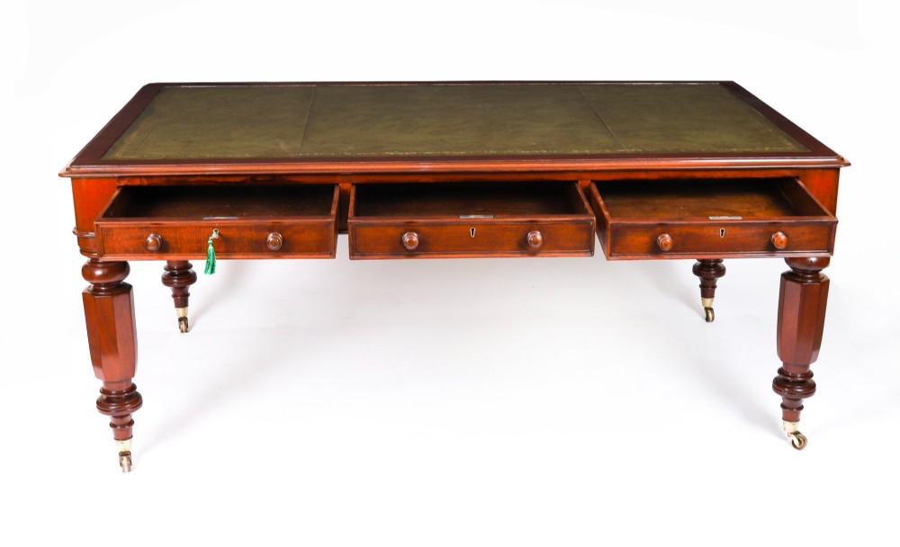 A nineteenth-century mahogany partners writing table featuring a green leather inset surface, six drawers with turned knobs, and octagonal turned legs on brass castors. View XI