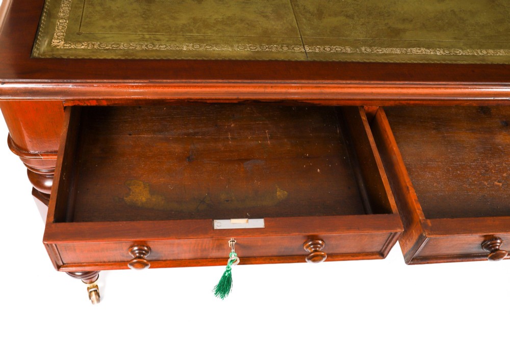 A nineteenth-century mahogany partners writing table featuring a green leather inset surface, six drawers with turned knobs, and octagonal turned legs on brass castors. View XII