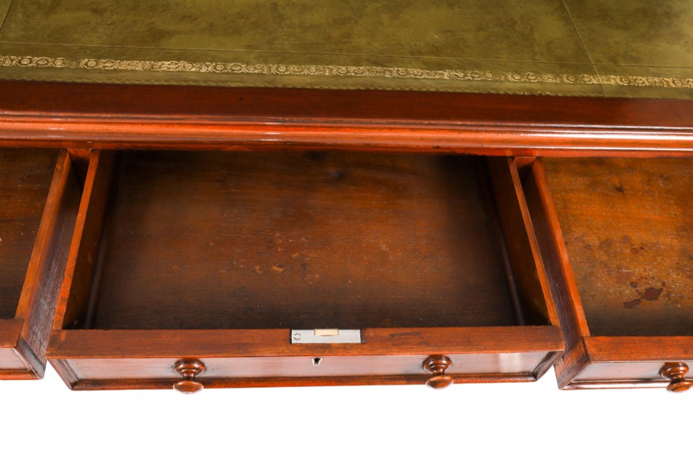 A nineteenth-century mahogany partners writing table featuring a green leather inset surface, six drawers with turned knobs, and octagonal turned legs on brass castors. View XIII