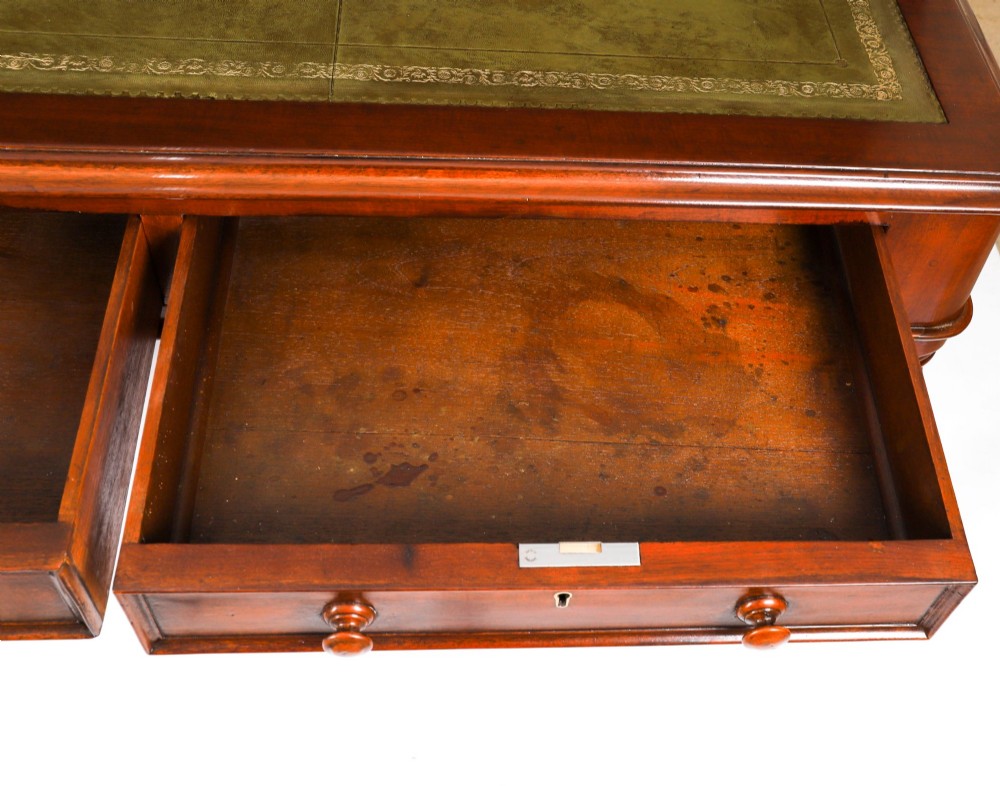 A nineteenth-century mahogany partners writing table featuring a green leather inset surface, six drawers with turned knobs, and octagonal turned legs on brass castors. View XIV