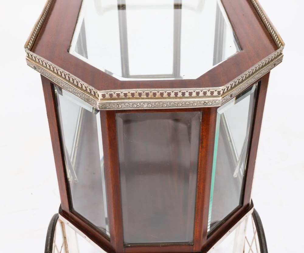 An Art Deco drinks trolley featuring an octagonal glass top with metal gallery trim, wooden side frames, spoked wheels, and a drop-down door. View VII