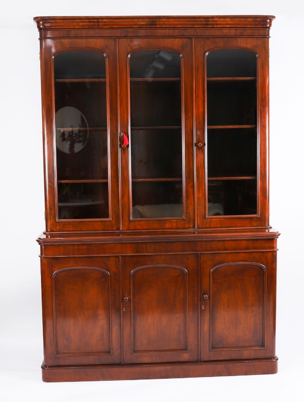 A large 19th-century Victorian flame mahogany library bookcase featuring a glazed three-door upper section filled with books above a solid three-door cupboard base. View II