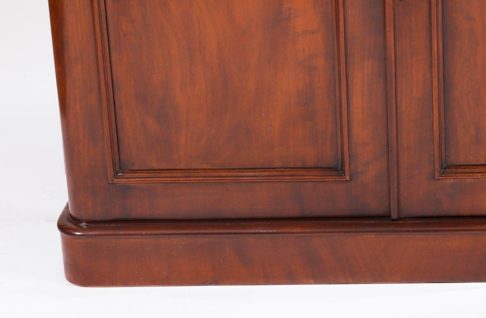 A large 19th-century Victorian flame mahogany library bookcase featuring a glazed three-door upper section filled with books above a solid three-door cupboard base. View VI