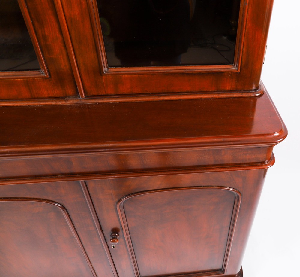 A large 19th-century Victorian flame mahogany library bookcase featuring a glazed three-door upper section filled with books above a solid three-door cupboard base. View VII