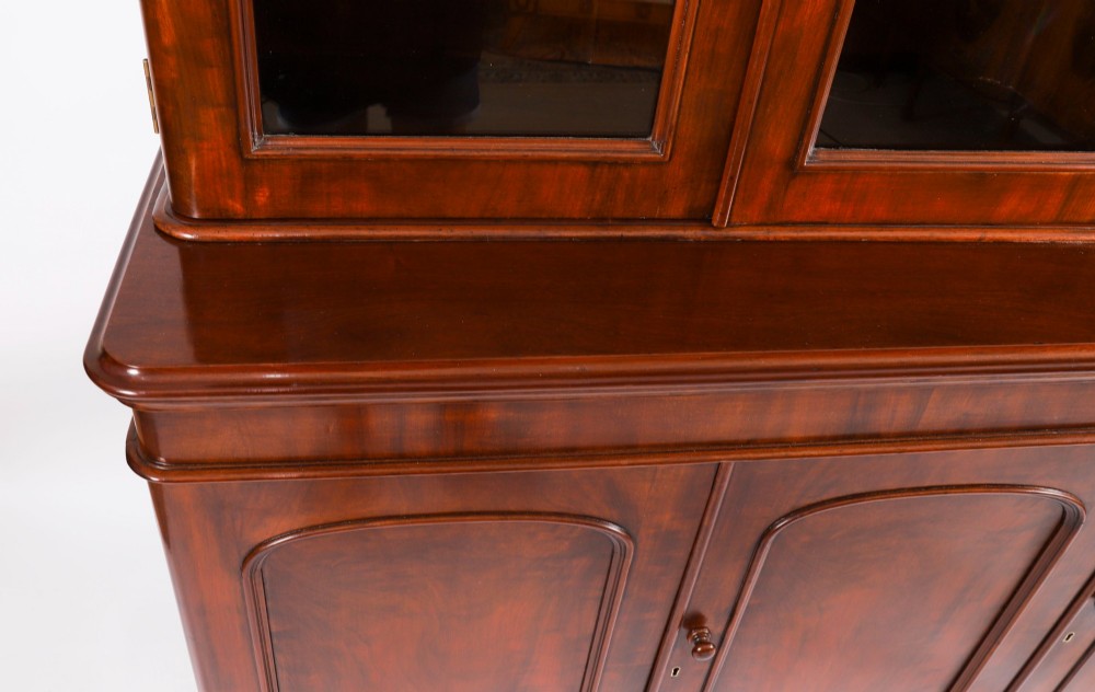 A large 19th-century Victorian flame mahogany library bookcase featuring a glazed three-door upper section filled with books above a solid three-door cupboard base. View VIII