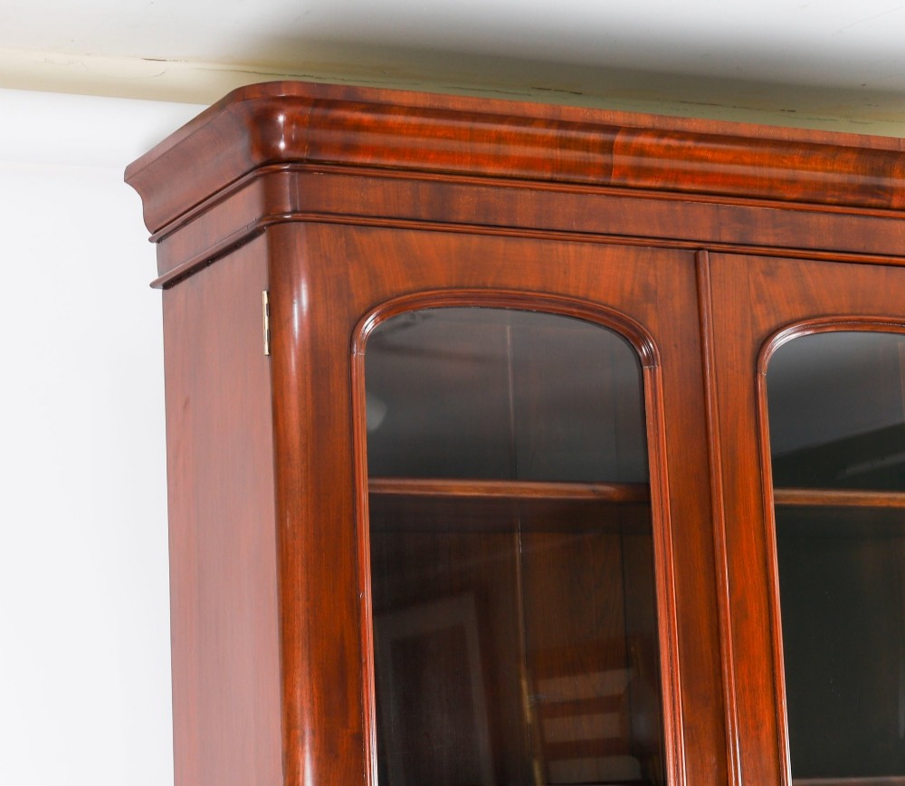 A large 19th-century Victorian flame mahogany library bookcase featuring a glazed three-door upper section filled with books above a solid three-door cupboard base. View IX