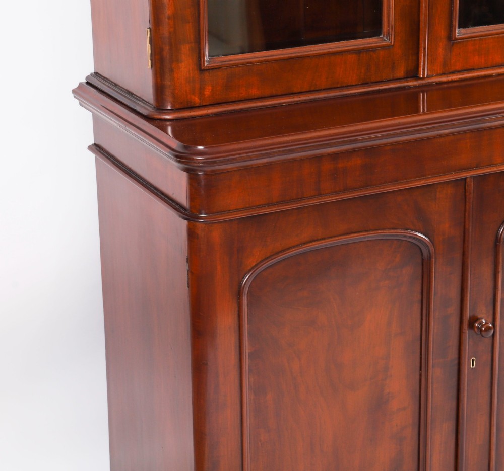 A large 19th-century Victorian flame mahogany library bookcase featuring a glazed three-door upper section filled with books above a solid three-door cupboard base. View X