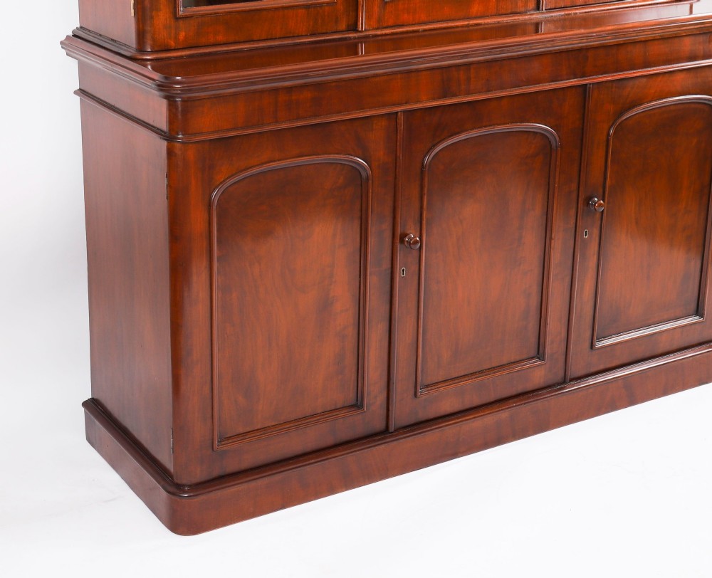 A large 19th-century Victorian flame mahogany library bookcase featuring a glazed three-door upper section filled with books above a solid three-door cupboard base. View XI