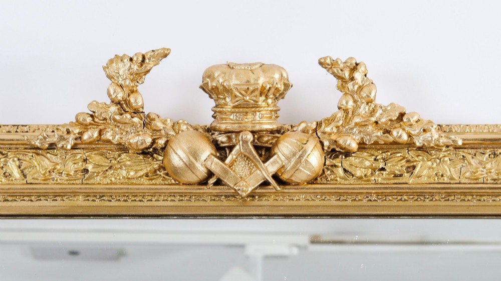 A rectangular nineteenth-century gold giltwood mirror featuring carved Masonic emblems, floral mouldings, and a crest. View II