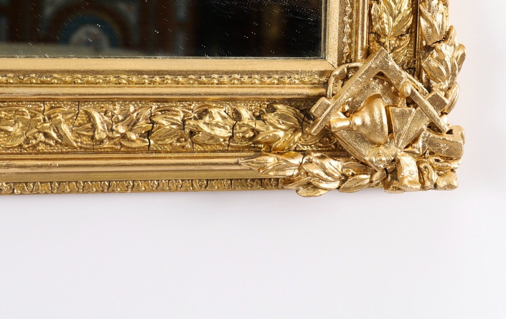 A rectangular nineteenth-century gold giltwood mirror featuring carved Masonic emblems, floral mouldings, and a crest. View VI