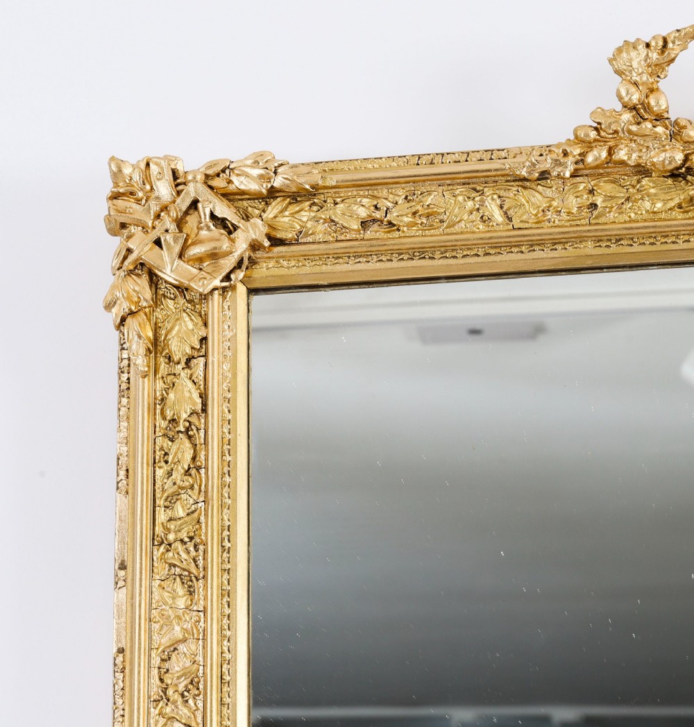 A rectangular nineteenth-century gold giltwood mirror featuring carved Masonic emblems, floral mouldings, and a crest. View VIII