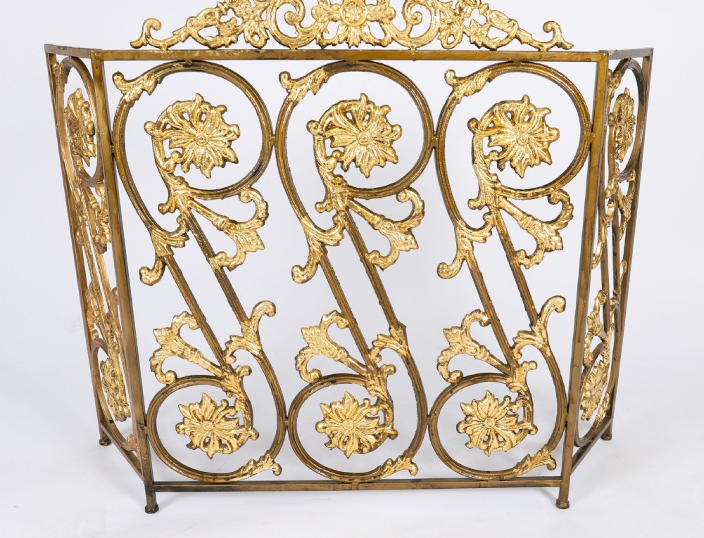 A nineteenth-century French Louis XIV Revival three-panel folding fire screen made from gilt brass featuring intricate floral scrollwork and an ornate cresting motif. View II
