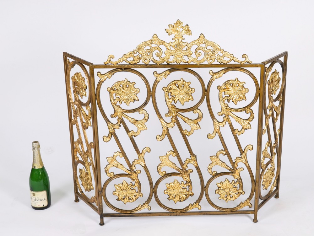 A nineteenth-century French Louis XIV Revival three-panel folding fire screen made from gilt brass featuring intricate floral scrollwork and an ornate cresting motif. View IX