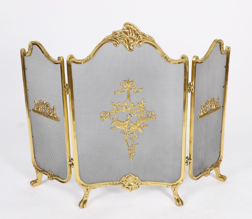 A three-fold French Rococo gilt bronze fire screen featuring fine wire mesh panels, ornate scrollwork cresting, and a central flaming torch motif.