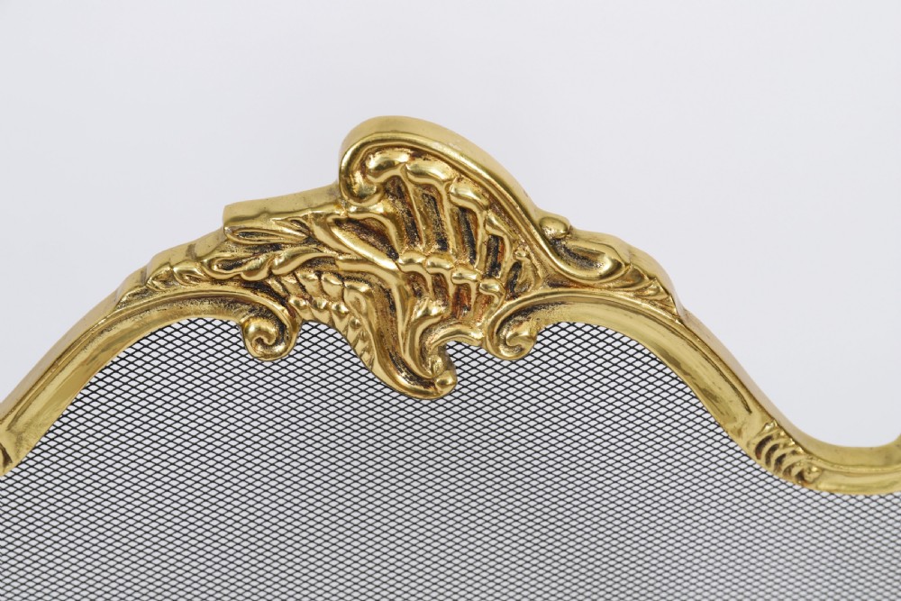 A three-fold French Rococo gilt bronze fire screen featuring fine wire mesh panels, ornate scrollwork cresting, and a central flaming torch motif. View V