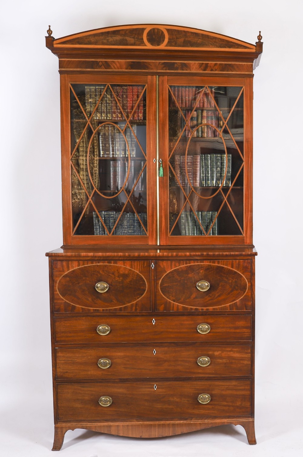 A George III flame mahogany secretaire bookcase featuring an arched pediment, astragal glazed doors, and lower drawers on bracket feet.