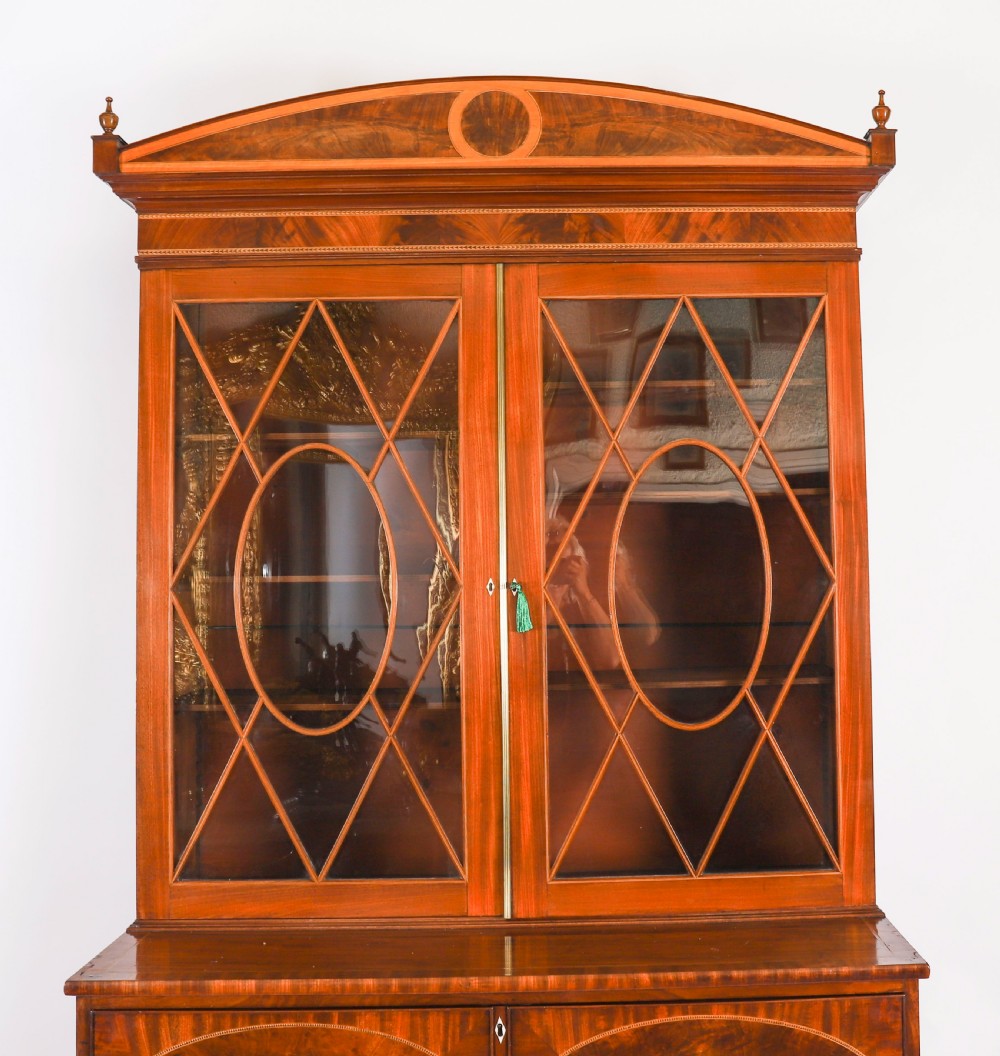 A George III flame mahogany secretaire bookcase featuring an arched pediment, astragal glazed doors, and lower drawers on bracket feet. View IV