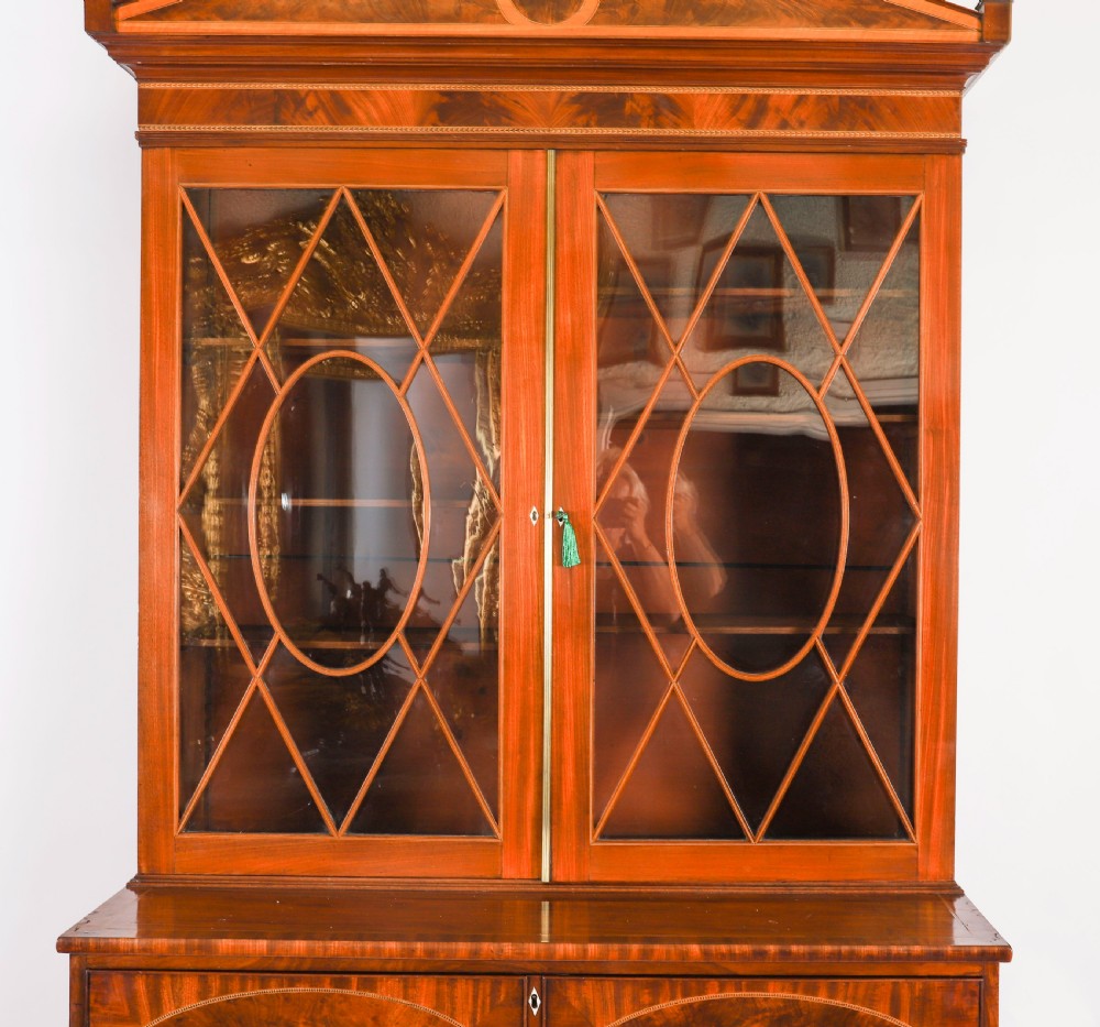 A George III flame mahogany secretaire bookcase featuring an arched pediment, astragal glazed doors, and lower drawers on bracket feet. View V