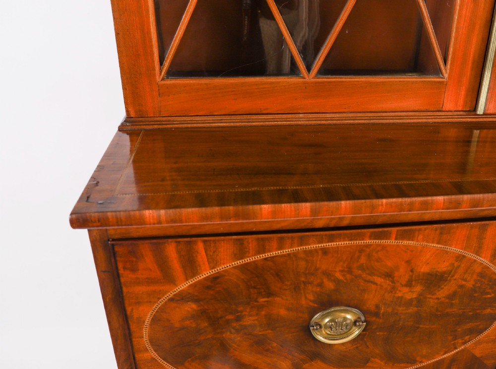 A George III flame mahogany secretaire bookcase featuring an arched pediment, astragal glazed doors, and lower drawers on bracket feet. View IX