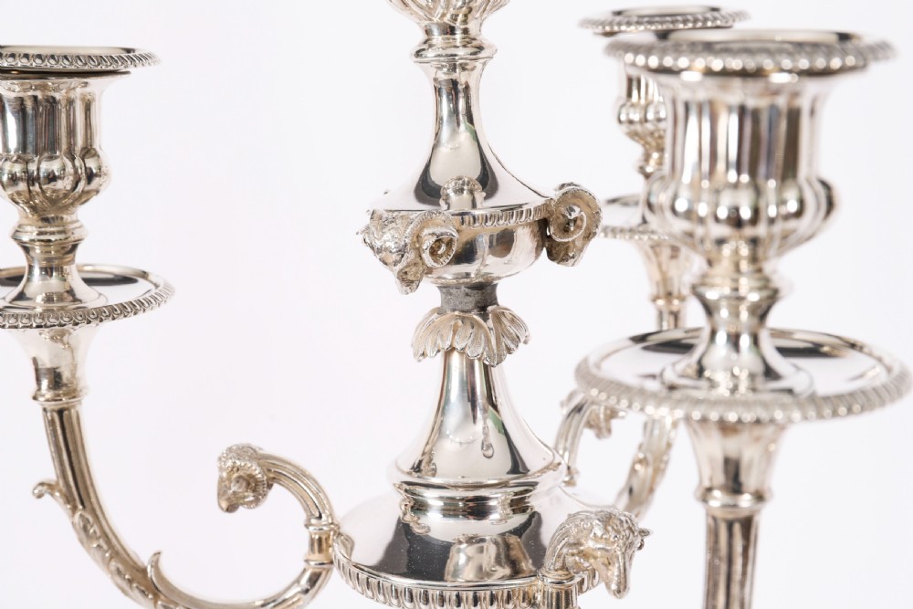 A pair of silver-plated four-light candelabra with fluted columns, scroll branches, and laurel wreath detailing on square bases. View V
