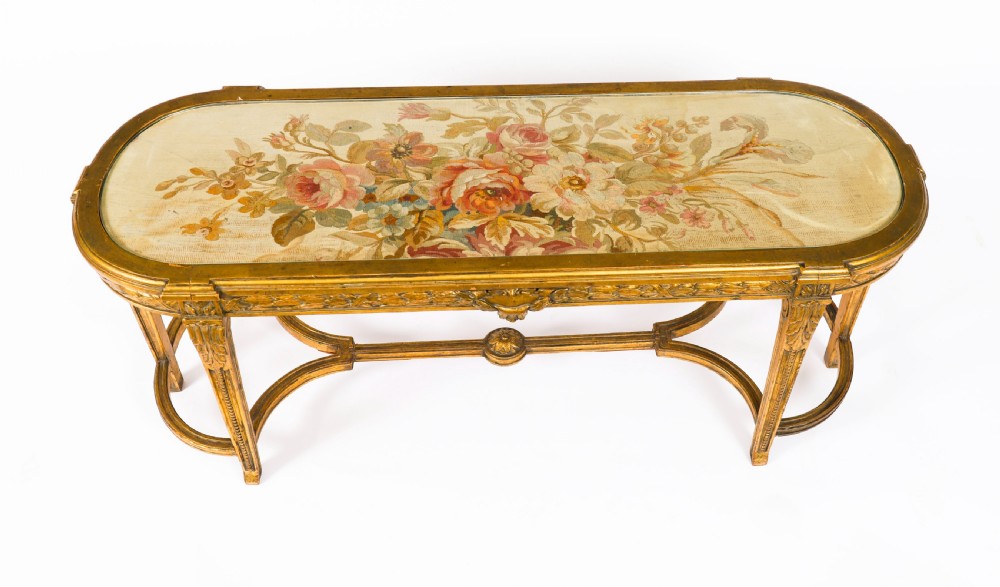 An early 20th-century oval French Louis XVI style giltwood low table featuring an inlaid tapestry top under glass and carved legs connected by a stretcher. View III