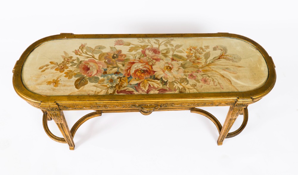 An early 20th-century oval French Louis XVI style giltwood low table featuring an inlaid tapestry top under glass and carved legs connected by a stretcher. View IV
