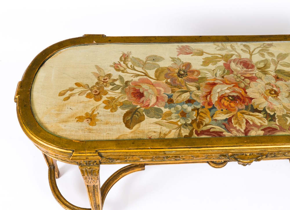 An early 20th-century oval French Louis XVI style giltwood low table featuring an inlaid tapestry top under glass and carved legs connected by a stretcher. View VI