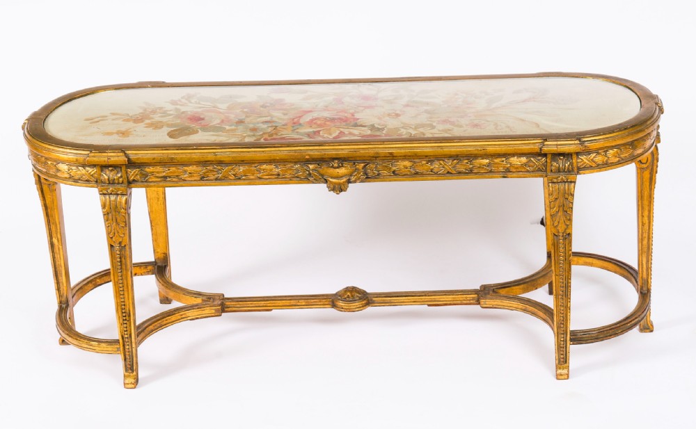An early 20th-century oval French Louis XVI style giltwood low table featuring an inlaid tapestry top under glass and carved legs connected by a stretcher. View VIII