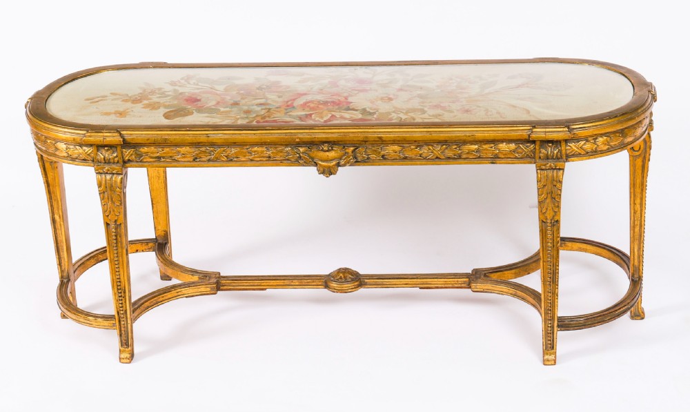 An early 20th-century oval French Louis XVI style giltwood low table featuring an inlaid tapestry top under glass and carved legs connected by a stretcher. View IX