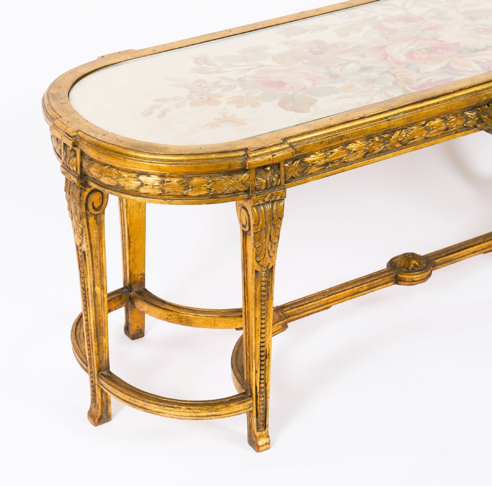 An early 20th-century oval French Louis XVI style giltwood low table featuring an inlaid tapestry top under glass and carved legs connected by a stretcher. View XI