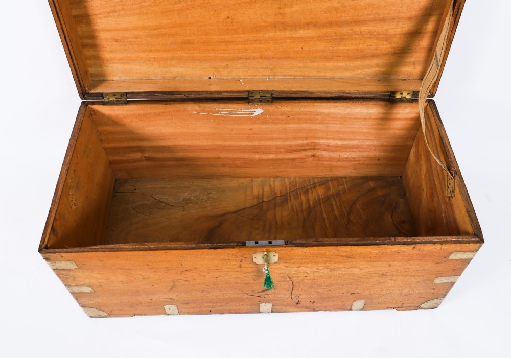 A rectangular 19th-century warm brown camphorwood military campaign trunk featuring flush brass corner brackets, protective metal straps, side drop handles, and a central brass keyhole escutcheon. View IV