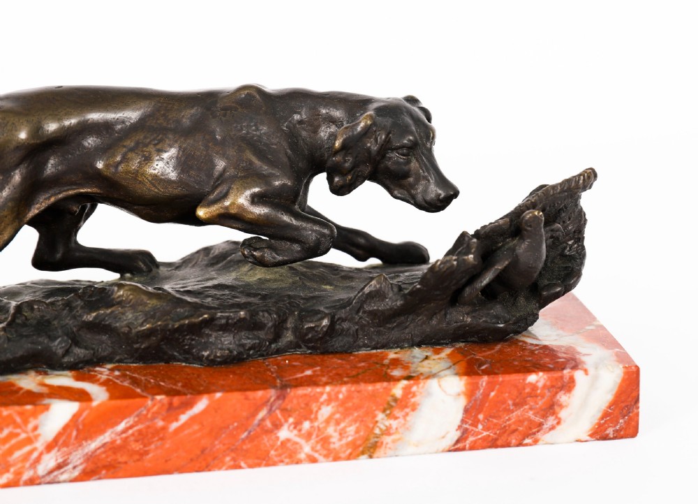 A dark brown patinated bronze sculpture of a hunting dog stalking prey, mounted on a rectangular red and white veined marble base. View V