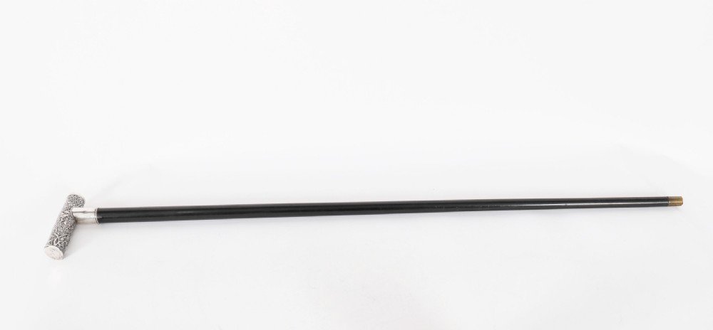 An antique walking stick featuring a relief-carved silver handle decorated with prunus blossoms, set on a slender black ebonised wooden shaft with a brass tip.