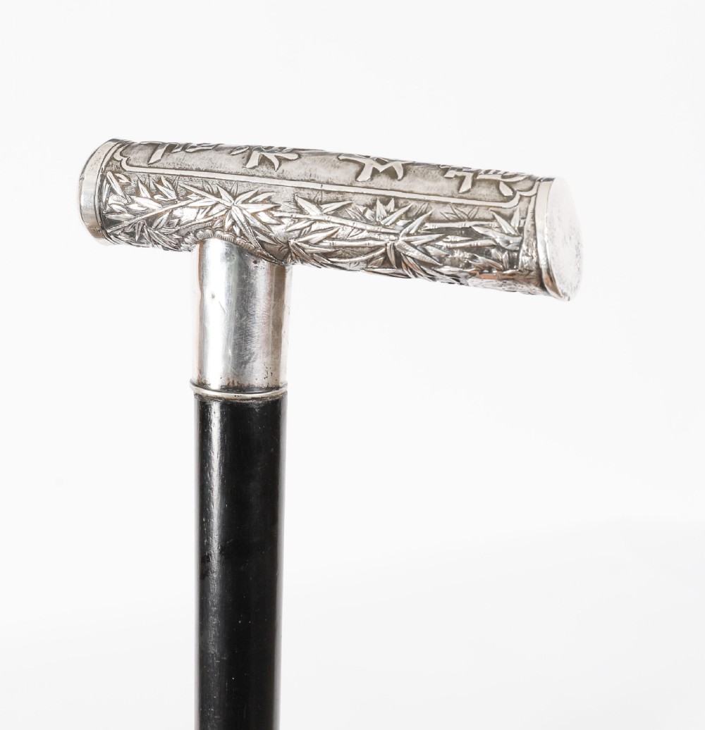An antique walking stick featuring a relief-carved silver handle decorated with prunus blossoms, set on a slender black ebonised wooden shaft with a brass tip. View XIII