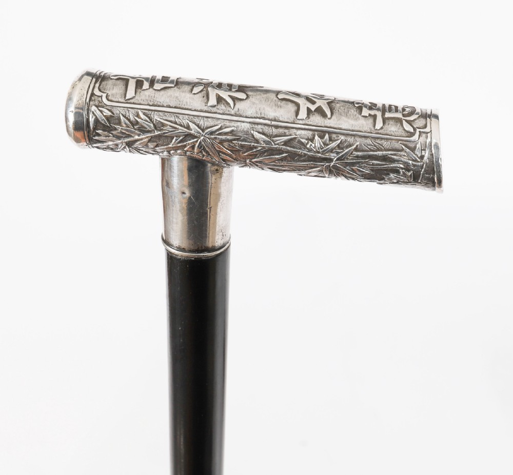 An antique walking stick featuring a relief-carved silver handle decorated with prunus blossoms, set on a slender black ebonised wooden shaft with a brass tip. View XIV