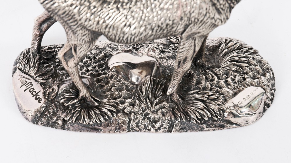 A detailed sterling silver sculpture of a standing stag with branching antlers positioned on a textured rocky ground base. View VIII