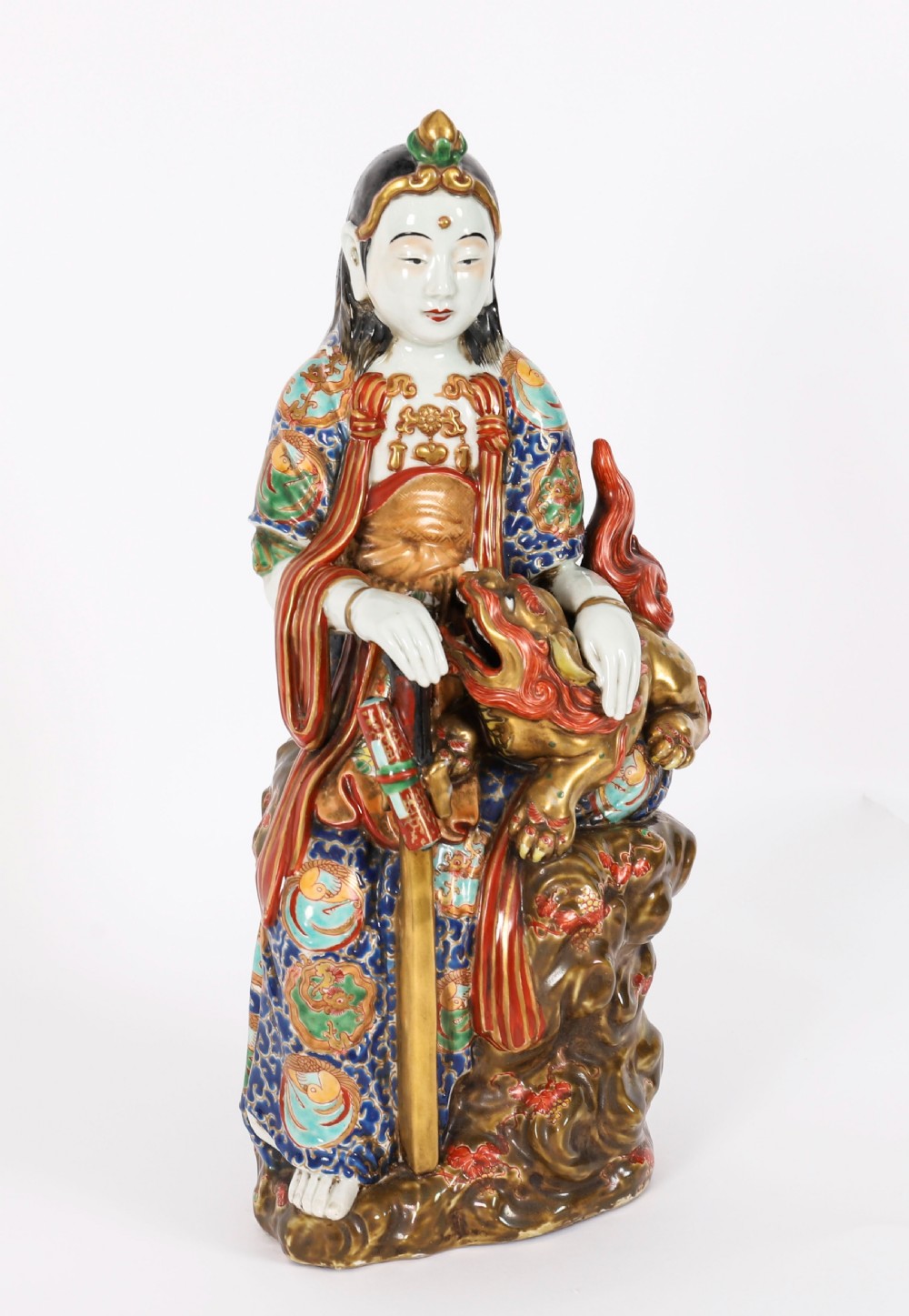 An antique Japanese Kutani porcelain sculpture depicting Guanyin standing beside a shishi lion with detailed polychrome drapery and gold leaf accents.