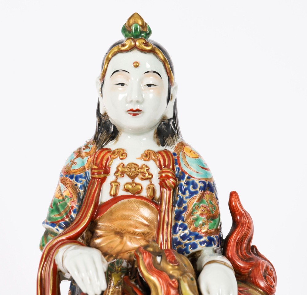 An antique Japanese Kutani porcelain sculpture depicting Guanyin standing beside a shishi lion with detailed polychrome drapery and gold leaf accents. View III